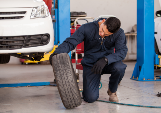 Repair technician changing old tire in service bay